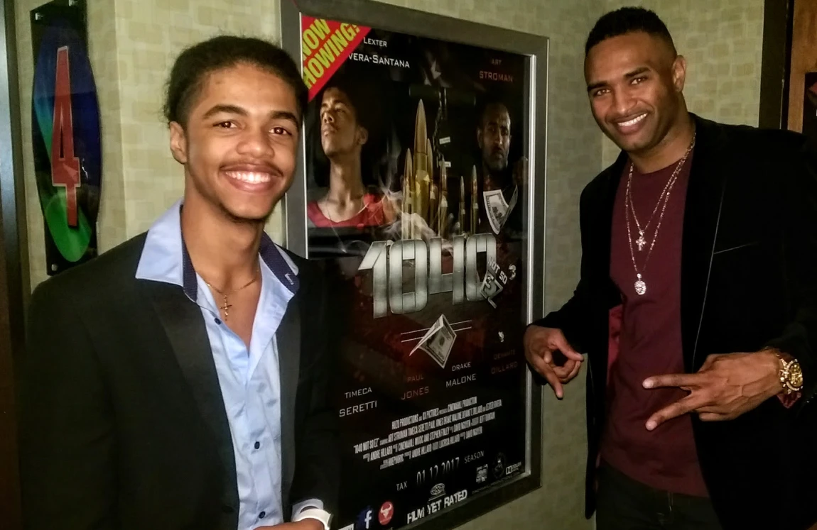 Two people posing by a movie poster.
